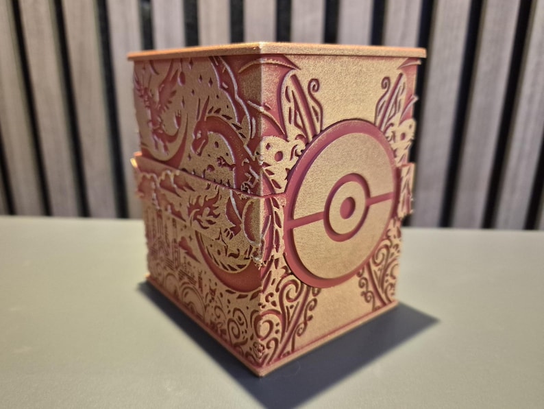 Peut inclure: Bo&icirc;te d&eacute;corative &agrave; couvercle articul&eacute;, avec des motifs d&eacute;coup&eacute;s au laser en or et rouge. La bo&icirc;te pr&eacute;sente un embl&egrave;me circulaire pro&eacute;minent avec un point central, entour&eacute; de motifs orn&eacute;s et de motifs de dragons. La bo&icirc;te est en bois.