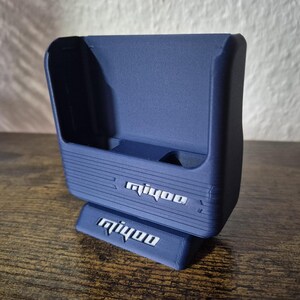 May include: A blue plastic stand with the word "mijoo" printed on it. The stand has a slot for a phone or other device.