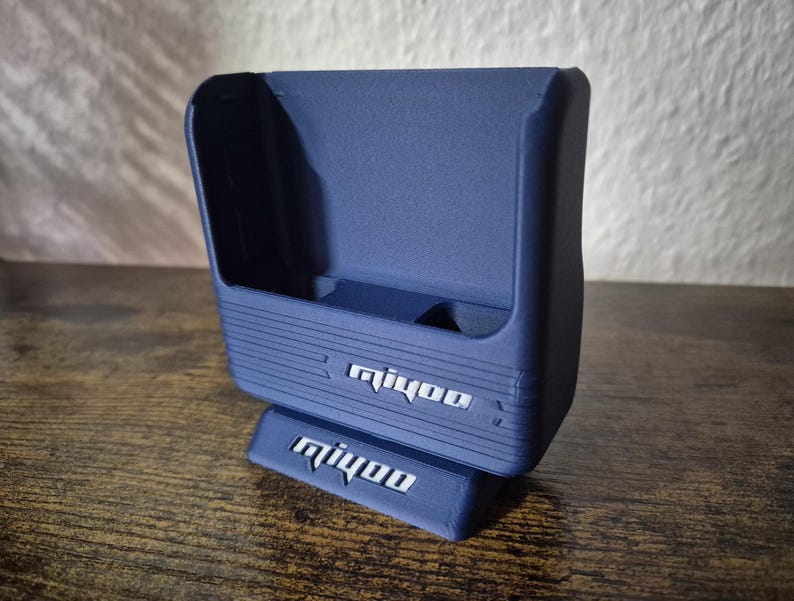 May include: A blue plastic stand with the word "mijoo" printed on it. The stand has a slot for a phone or other device.