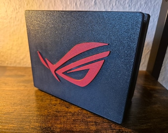 May include: A black rectangular box with a red and black logo. The logo is a stylized letter "G" with a diagonal line through it.