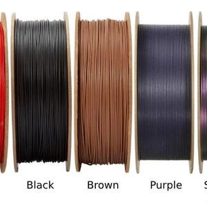 Peut inclure: Plusieurs bobines de filament de diff&eacute;rentes couleurs, dont vert, bleu, rouge, noir, marron, violet et des nuances nomm&eacute;es "Starlight Nebula", "Starlight Comet" et "Starlight Neptune". Chaque bobine est &eacute;tiquet&eacute;e avec sa couleur.