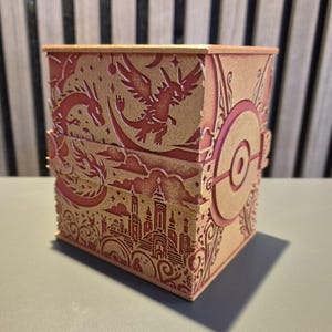 Peut inclure: Une bo&icirc;te d&eacute;corative avec des motifs d&eacute;coup&eacute;s au laser complexes. La bo&icirc;te pr&eacute;sente une palette de couleurs rouge et or, avec des illustrations de dragons, d'une ville et d'un embl&egrave;me circulaire. La bo&icirc;te est rectangulaire et poss&egrave;de un couvercle &agrave; charni&egrave;re.