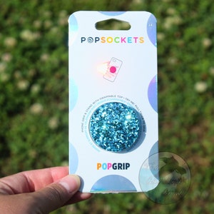 May include: A blue glitter PopSocket phone grip with the text "PopGrip" and "PopSockets" on the packaging.