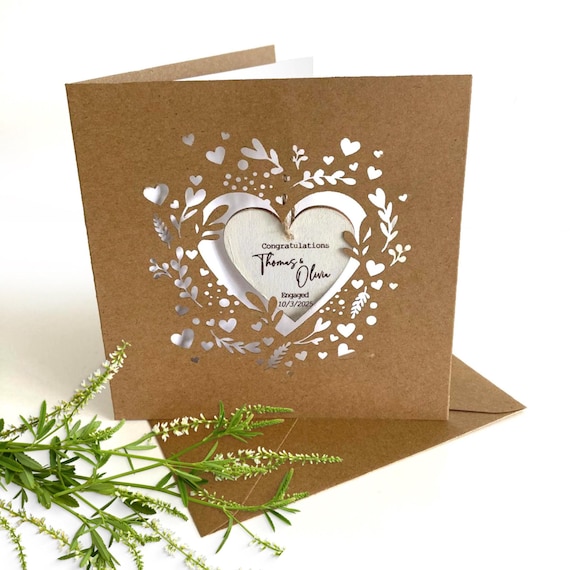 A laser-cut 3D paper sculpture card with custom names and date — it's simultaneously the card AND the keepsake, the kind of thing you frame instead of recycle.