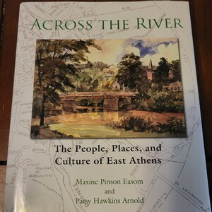 May include: Book cover with a watercolor illustration of a bridge over a river with trees and a church building in the background. The title of the book is "Across the River: The People, Places, and Culture of East Athens" by Maxine Pinson Easom and Patsy Hawkins Arnold. The book cover also includes a map of East Athens.