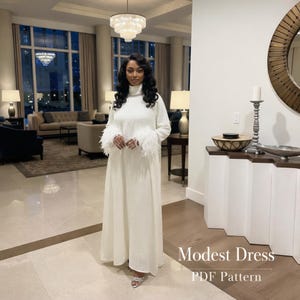 May include: A long, white modest dress with a high neckline and long sleeves. The sleeves are trimmed with white feathers. The dress is floor-length and has a simple, elegant design. The text "Modest Dress PDF Pattern" is visible.