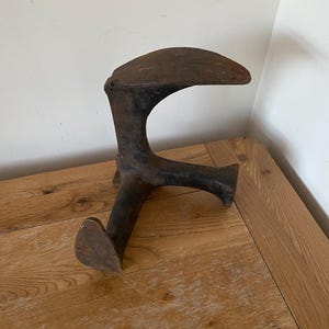 May include: A vintage metal shoe last, a tool used by cobblers to shape and repair shoes. The last is made of cast iron and has a dark brown patina.