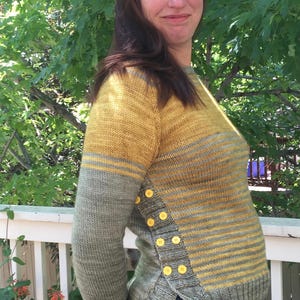 Puede incluir: Un suéter a rayas en tonos amarillos y verdes con una fila de botones amarillos en el lateral.