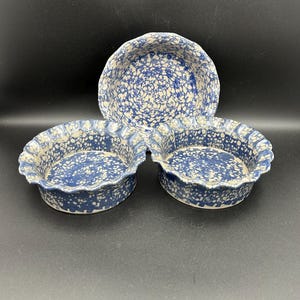 May include: Three blue and white ceramic pie plates with a scalloped edge. The plates have a speckled glaze pattern.