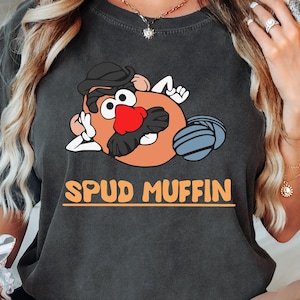 May include: A dark gray t-shirt with a cartoon image of Mr. Potato Head with the text "Spud Muffin".