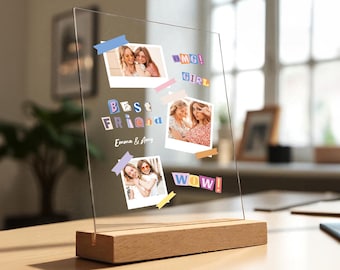 May include: A clear acrylic photo display with a wooden base. The display features three photos of two women, with the words "Best Friend," "OMG! GIRL," and "WOW!" in colorful lettering. The names "Emma & Amy" are also visible.