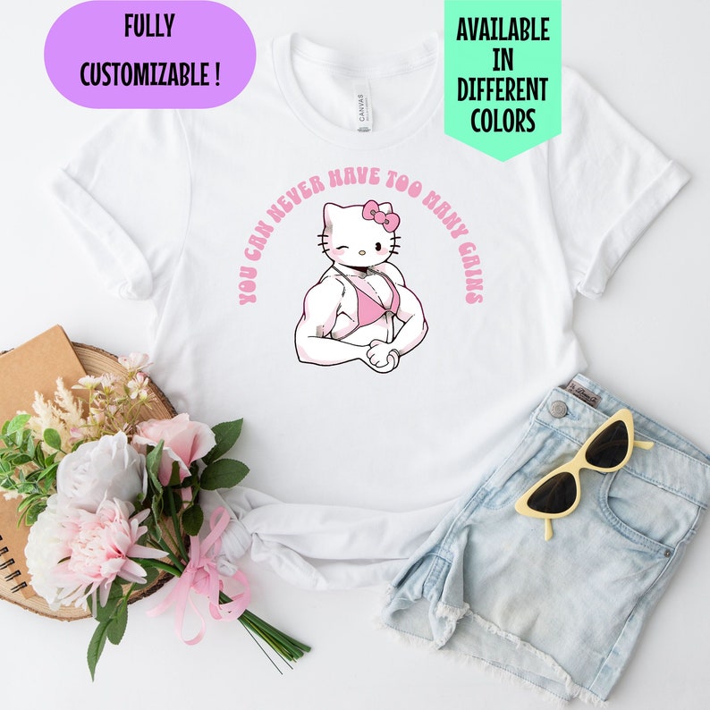 May include: White t-shirt with a pink Hello Kitty graphic wearing a pink bikini and flexing her muscles. The text "You can never have too many gains" is written in a pink circle around Hello Kitty.