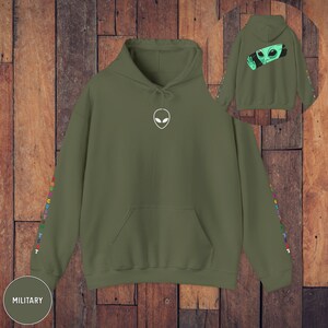 Peut inclure: Un sweat &agrave; capuche vert militaire avec un graphique d'extraterrestre blanc sur le devant et du texte color&eacute; sur les manches. Le texte dit "YOU ARE CUSTOM TEXT".