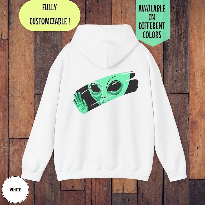 Peut inclure: Sweat-shirt &agrave; capuche blanc avec un extraterrestre vert qui sort d'un coup de pinceau noir sur le dos. Le texte "FULLY CUSTOMIZABLE!" est en jaune en haut et "AVAILABLE IN DIFFERENT COLORS" est en noir en haut &agrave; droite. Le mot "WHITE" est en blanc en bas &agrave; gauche.