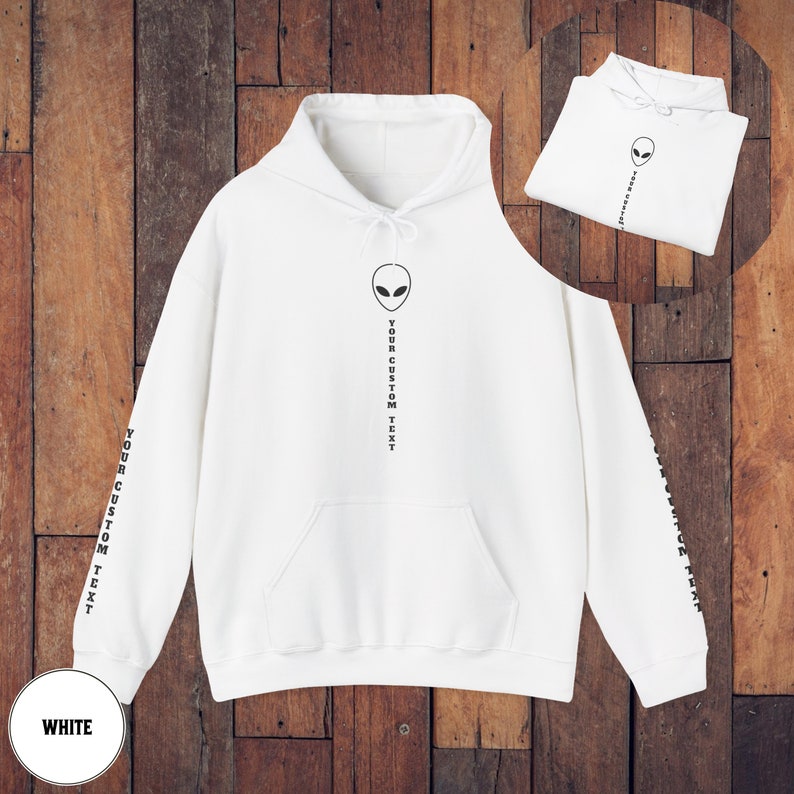 Peut inclure: Sweat-shirt &agrave; capuche blanc avec un motif d'alien noir et le texte "YOUR CUSTOM TEXT" imprim&eacute; verticalement sur le devant et les manches.