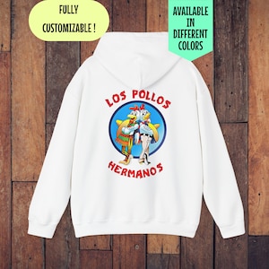 Peut inclure: Sweat-shirt à capuche blanc avec un imprimé graphique de deux poulets de dessin animé portant des sombreros et le texte "Los Pollos Hermanos".