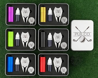 Könnte beinhalten: Golf-Geschenksets in verschiedenen Farben, darunter Lila, Gold, Grün, Schwarz, Blau und Rot. Jedes Set enthält einen zylindrischen Gegenstand, eine kleine Flasche, ein Pitchgabel und eine Ballmarkierung, alles in einer Metalldose. Auf der Dose rechts ist das "PUILCO"-Logo.