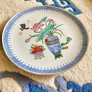 10.25” Chinese Porcelain Plate w/ Hand-Painted Lotus Vase, Fruit, & Calligraphy – Blue Greek Key Border, Red Mark, Chinoiserie Wall Decor