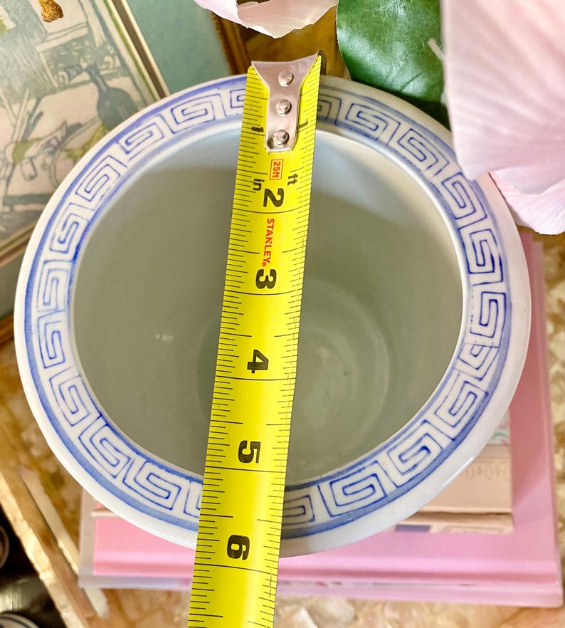 May include: A white ceramic planter with a blue and white geometric pattern around the rim. The planter is 6 inches in diameter.