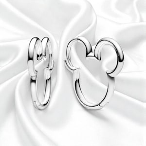 Pu&ograve; includere: Un paio di orecchini a cerchio color argento. Uno &egrave; a forma di testa di topo classica, l'altro &egrave; un semplice cerchio. Gli orecchini sono presentati su uno sfondo bianco e setoso.