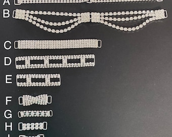 May include: A collection of nine rhinestone shoe straps in various designs. The straps are silver-colored and feature different patterns, including straight lines, geometric shapes, and a bow. Each strap has a metal buckle for attachment.