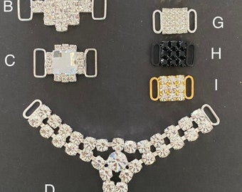 May include: Assortment of silver, gold, and black shoe buckles with crystal and rhinestone embellishments.  The buckles are labeled A through I.  A Y-shaped shoe buckle with crystal embellishments is labeled D.