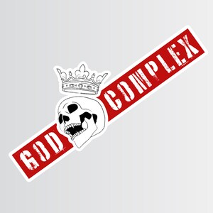 May include: A red and white sticker with the text "GOD COMPLEX" in white lettering. A black and white illustration of a skull wearing a crown is on the sticker.