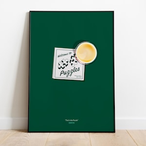 Könnte beinhalten: Gerahmtes Poster mit dunkelgrünem Hintergrund. Das Poster zeigt ein weißes Schild mit der Aufschrift "Welcome to Puzzles" mit Puzzleteil-Grafiken. Oben rechts befindet sich eine Tasse Kaffee. Der Satz "That's the Puzzle" steht unten.