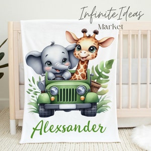 Puede incluir: Una manta de beb&eacute; blanca con un jeep verde, un elefante y una jirafa. El jeep tiene una cesta verde en el lateral. El elefante conduce el jeep y la jirafa est&aacute; sentada en el asiento del pasajero. La manta tiene el nombre "Alexander" escrito en letras verdes en la parte inferior.