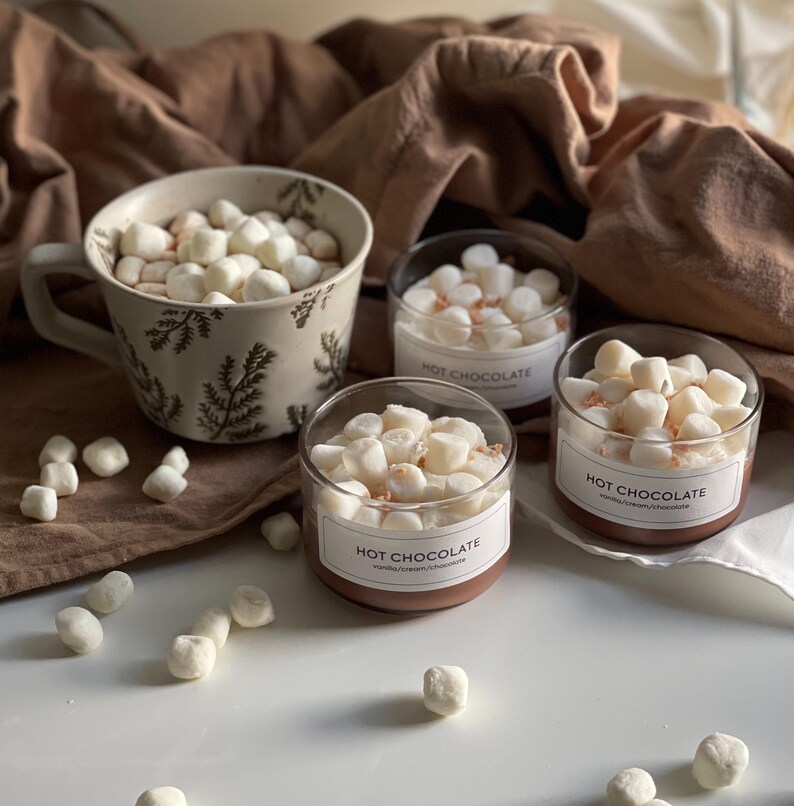 Pode incluir: Uma caneca de cer&acirc;mica e tr&ecirc;s potes de vidro cheios de chocolate quente e marshmallows. A caneca tem um padr&atilde;o de samambaia. Os potes t&ecirc;m r&oacute;tulos que dizem "Hot Chocolate". Marshmallows espalhados.