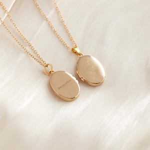May include: Two gold-toned oval locket necklaces with delicate chains. One locket features an engraved butterfly design, while the other locket displays the engraved text "love you always" in a cursive script on its smooth, polished surface.