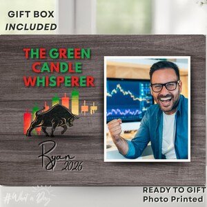 May include: A wooden photo frame with the text "THE GREEN CANDLE WHISPERER" in green and red. The frame includes a photo of a man smiling and a bull graphic. The text "Ryan 2026" is also present. The words "GIFT BOX INCLUDED" and "READY TO GIFT Photo Printed" are also visible.
