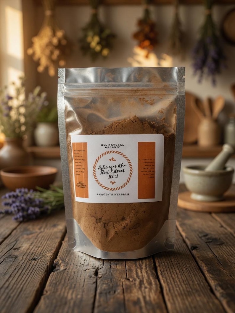 May include: A clear, resealable pouch filled with brown powder, labeled "Ashwagandha Root Extract 100:1" and "All Natural Organics." The pouch sits on a rustic wooden surface, with dried herbs and kitchen tools in the background. The brand name "Shaggy's Herbals" is also visible.