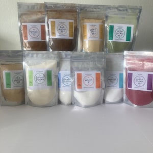 May include: A collection of clear, resealable pouches filled with various powders. Each pouch has a label with text such as "Collagen Peptides" and "Vitamin C". The powders are in shades of beige, white, and red.