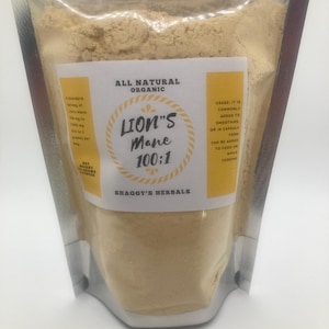 May include: A clear, sealed bag filled with light brown powder. The bag has a white and yellow label with the text "ALL NATURAL ORGANIC" and "LION'S Mane 100:1". The label also includes usage instructions and the brand name "SHAGGY'S HERBALS".