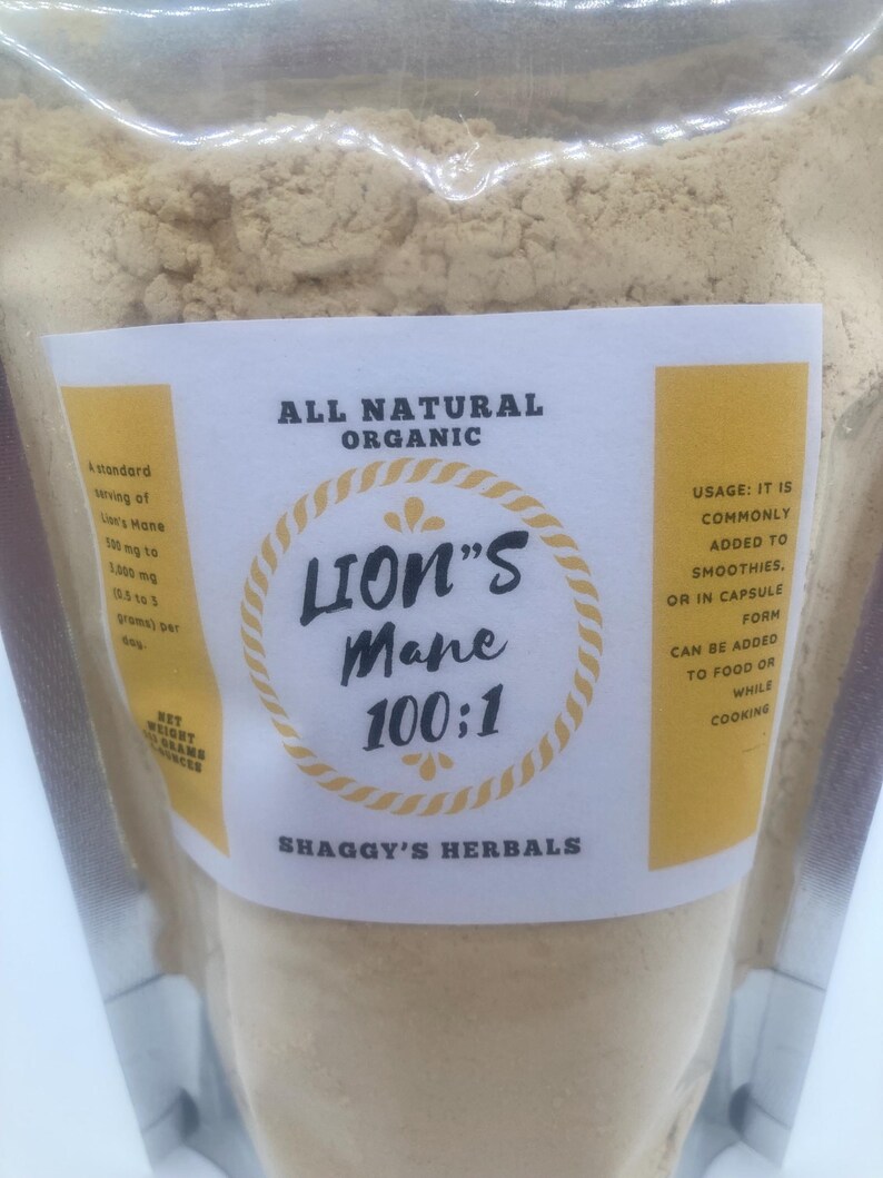 May include: A clear plastic bag filled with a light brown powder. The bag has a white label with the text "ALL NATURAL ORGANIC" and "LION'S Mane 100:1". The label also includes the text "SHAGGY'S HERBALS".