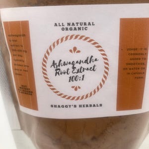 May include: A clear plastic bag filled with brown powder. The label reads "Ashwagandha Root Extract 100:1" with "All Natural Organic" above and "Shaggy's Herbals" below. The net weight is 113 grams or 4 ounces.