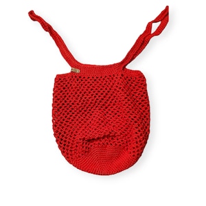 May include: Red crocheted tote bag with a brown leather tag. The bag has a mesh design and two long straps.