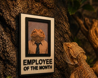 May include: A rectangular wall plaque featuring a portrait of a bearded dragon wearing a tan shirt and a dark tie. Below the portrait, the text EMPLOYEE OF THE MONTH is displayed in black, bold, raised lettering against a white background.