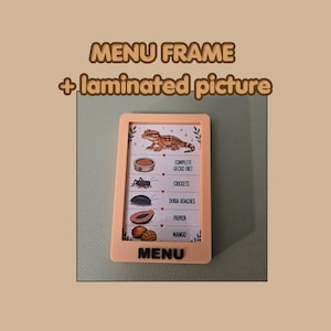 May include: A light peach-colored rectangular menu frame containing a laminated picture of a gecko and its food items. The text reads MENU FRAME + laminated picture, and the list includes COMPLETE GECKO DIET, CRICKETS, DUBIA ROACHES, PAPAYA, and MANGO.