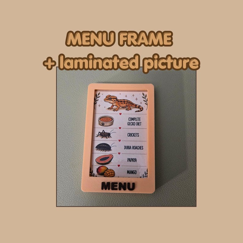 May include: A light peach-colored rectangular menu frame containing a laminated picture of a gecko and its food items. The text reads MENU FRAME + laminated picture, and the list includes COMPLETE GECKO DIET, CRICKETS, DUBIA ROACHES, PAPAYA, and MANGO.