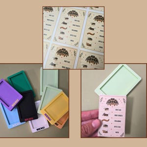 May include: A collection of rectangular silicone frames in various colors including purple, green, black, yellow, and light blue, each with the word MENU printed on the front. Also shown are printed cards featuring a spider and insect food list.