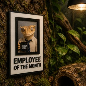 May include: A rectangular wall plaque featuring a framed portrait of a gecko wearing a dress shirt and tie, holding a black mug with the text MONDAY AGAIN. Below the portrait, the text EMPLOYEE OF THE MONTH is displayed in black lettering.