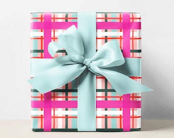 May include: A wrapped gift with a pink, red, and teal plaid pattern. The gift is tied with a light blue ribbon and bow. The background is plain white.