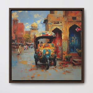 Puede incluir: Impresión en lienzo enmarcada de un colorido paisaje urbano indio. La obra de arte representa un vibrante auto rickshaw frente a un edificio con puertas arqueadas. La escena está pintada con una paleta de colores cálidos, incluyendo rojos, naranjas y azules.