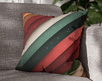 Pode incluir: Uma almofada quadrada decorativa com um design retro. Apresenta listras diagonais em tons de vermelho, verde, branco e marrom, com um padrão salpicado. A almofada está colocada em um sofá cinza, sugerindo um tema de decoração de casa. Aproximadamente 40 cm x 40 cm.