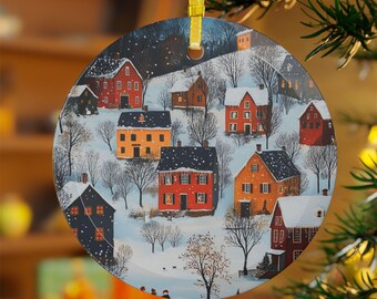 May include: Round glass Christmas ornament featuring a winter scene with snow-covered houses in a village. The houses are painted in shades of red, orange, yellow, and blue. The ornament is decorated with a white background and black outlines.