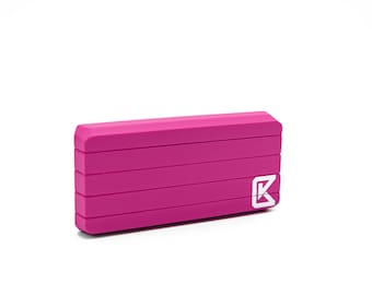 May include: A pink portable power bank with a white "K" logo. The power bank has a textured surface and is rectangular in shape.