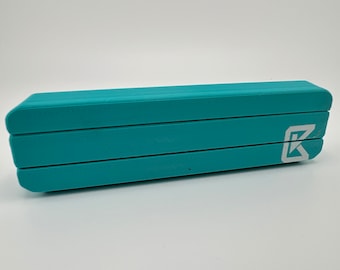May include: A teal blue, three-section, expandable, plastic utensil holder with a white "K" logo.
