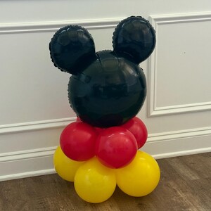 Pu&ograve; includere: Un'arrangiamento di palloncini a forma di testa di Topolino. La testa &egrave; nera, con due grandi orecchie rotonde. La base &egrave; composta da palloncini rossi e gialli, creando un'esposizione festosa.